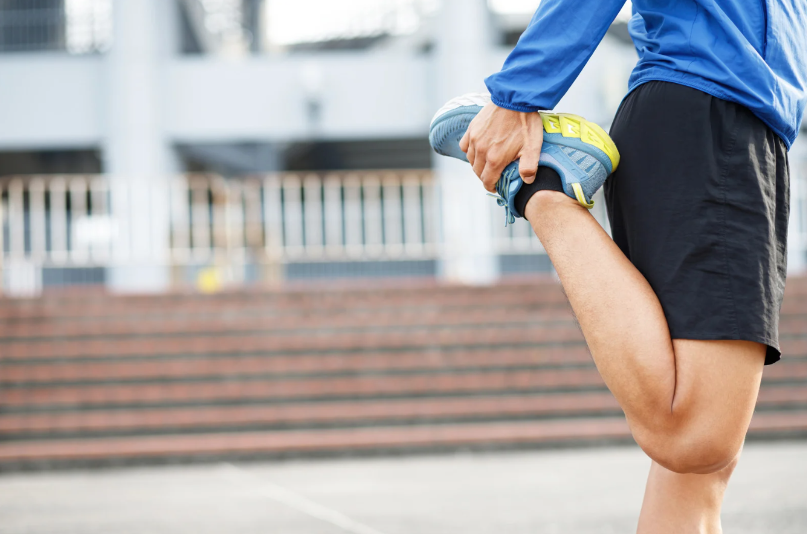 Athlete stretching by pulling one leg back to warm up before exercise.