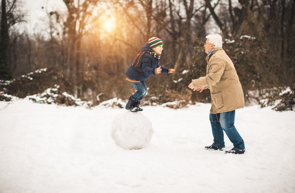 Grandfather playing in snow grandchild
